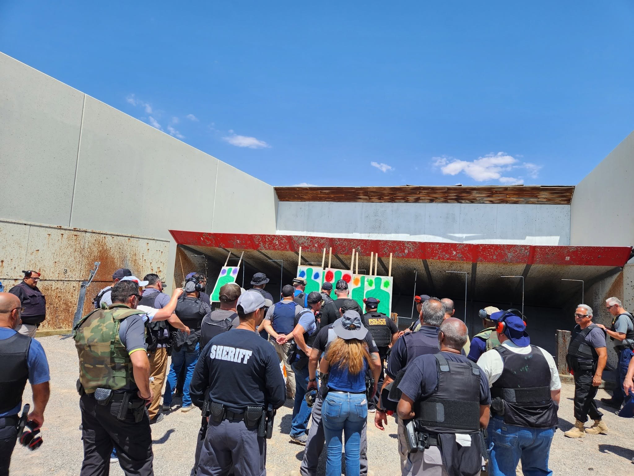 Officers gathered at the target line after a relay, comparing groups on the silhouettes.