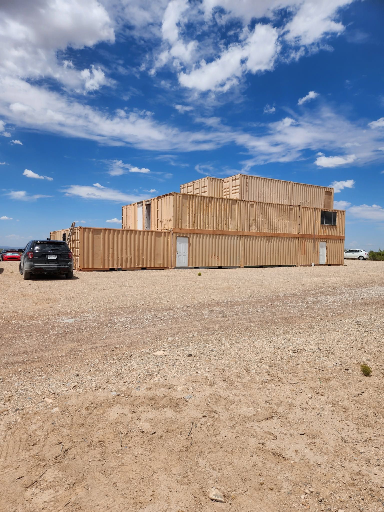 A shoot house built from stacked shipping containers under a West Texas sky.